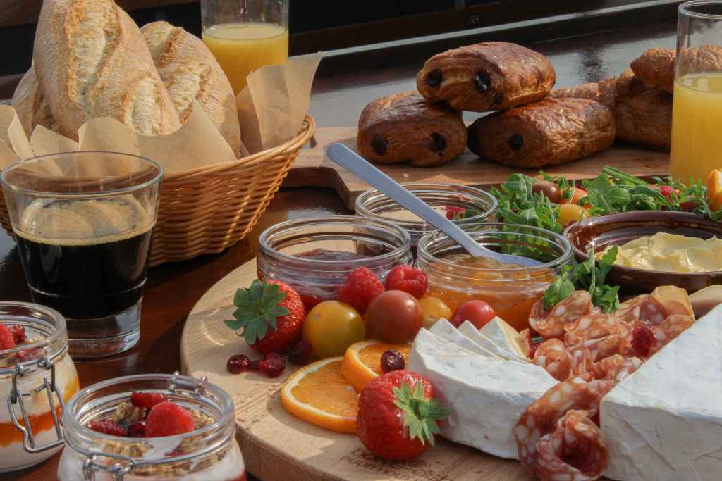 The Boat Café - Brunch & Breakfast boat with croissant, pain au chocolat, jam, butter, cheeses, ham and charuterie and breads, salads, granola bowls, coffee and juices
